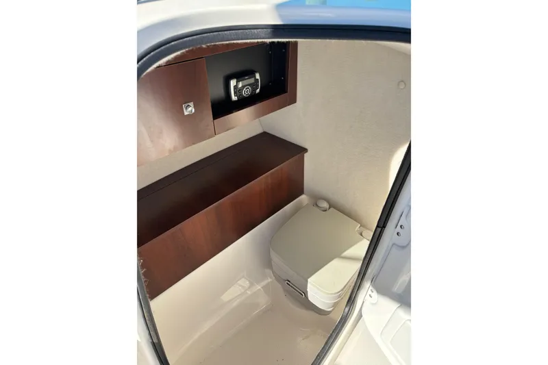 Slide: The Image of Interior of 2017 Robalo R227 Dual Console boat with compact marine toilet and storage. - 22