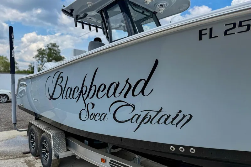 Slide: The Image of 2023 Sportsman Heritage 261 Center Console boat on trailer, parked outdoors under a cloudy sky. - 51