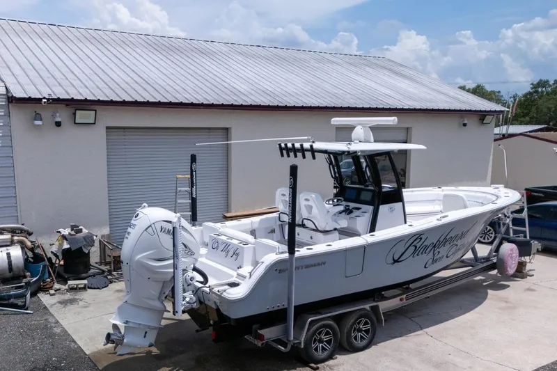 Slide: The Image of 2023 Sportsman Heritage 261 Center Console boat on trailer near a garage. - 97