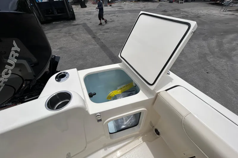 Slide: The Image of Open storage compartment on 2026 Scout 220 XSF boat, featuring a Mercury engine. - 10