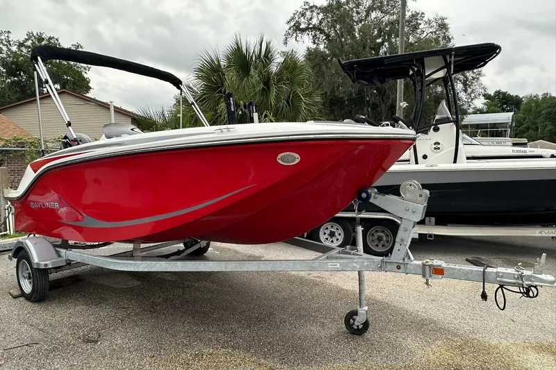 The Image of 2024 Bayliner Element M15 boat in vibrant red on a trailer, parked outdoors. - 1