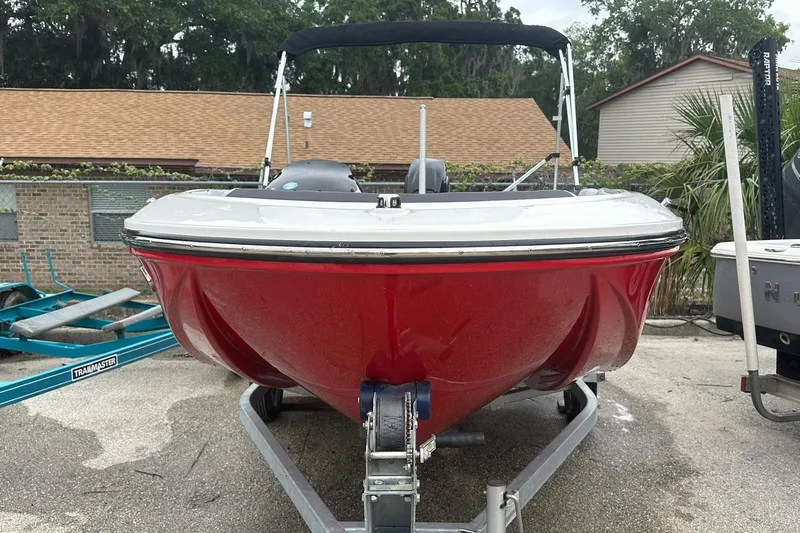 Slide: The Image of 2024 Bayliner Element M15 boat in vibrant red on a trailer, parked outdoors. - 3