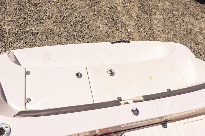 Slide: The Image of 2017 Yamaha Boats 190 FSH Sport deck, featuring storage compartments on a gravel surface. - 17