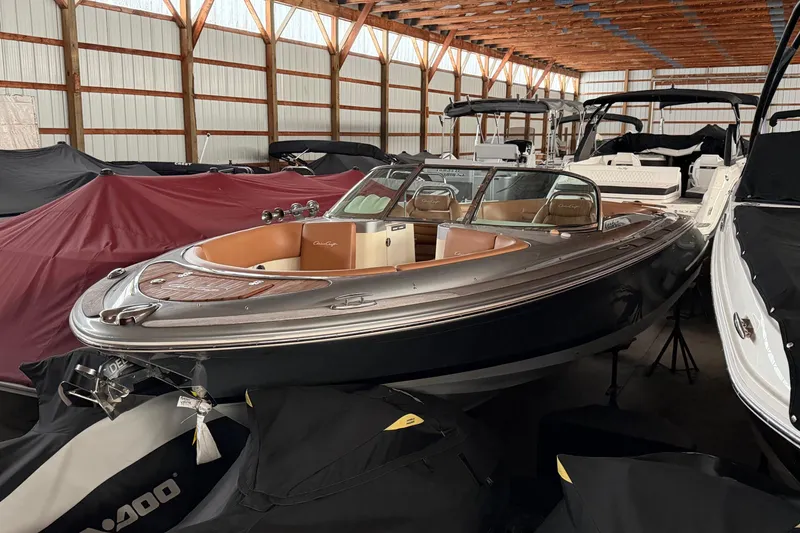 The Image of 2013 Chris-Craft Launch 25 boat in storage, surrounded by covered vessels. - 1