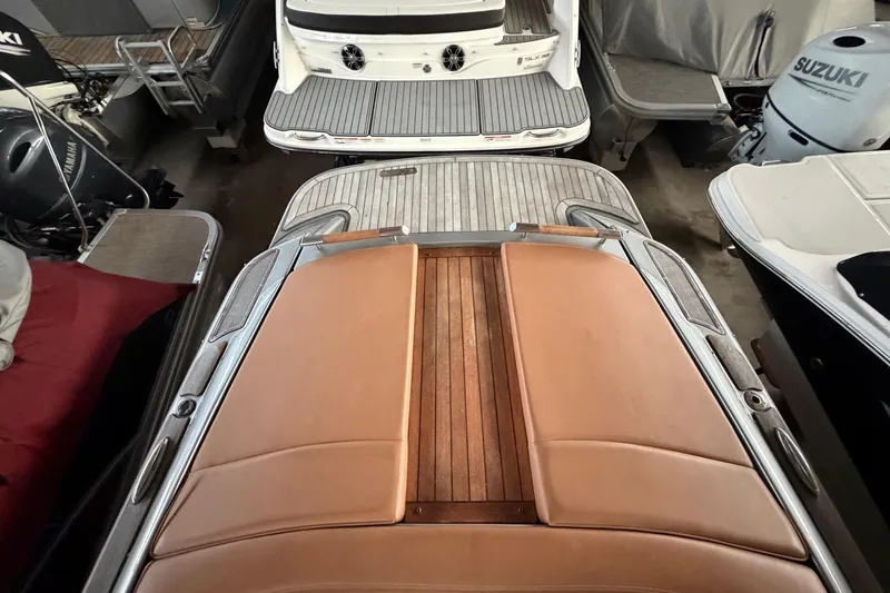 Slide: The Image of 2013 Chris-Craft Launch 25 boat with tan leather seating and wooden deck, docked indoors. - 12
