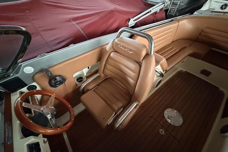 Slide: The Image of 2013 Chris-Craft Launch 25 boat interior with brown leather seating and wooden steering wheel. - 22