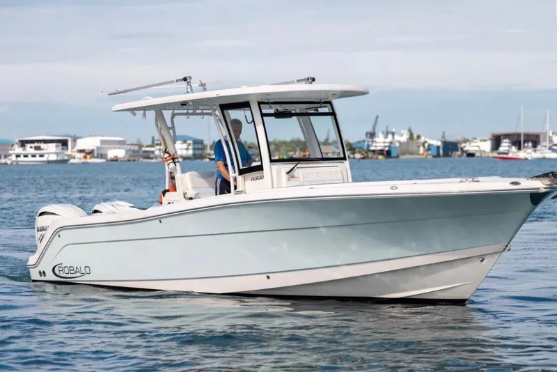 The Image of 2023 Robalo R302 Center Console boat cruising on calm waters near a marina. - 0