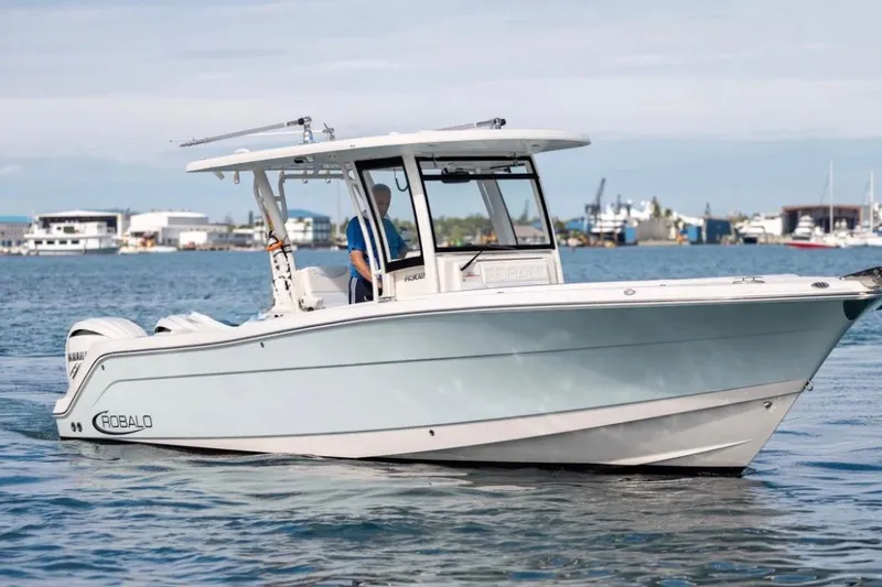 Slide: The Image of 2023 Robalo R302 Center Console boat cruising on calm waters near a marina. - 10