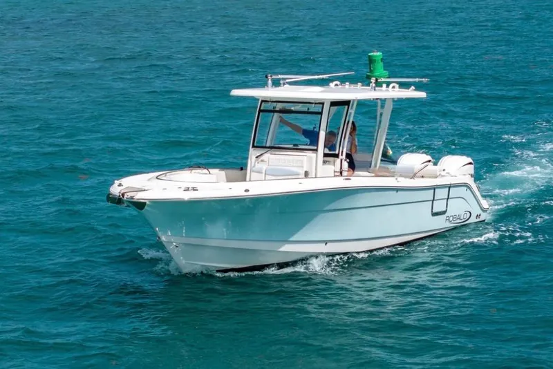 Slide: The Image of 2023 Robalo R302 Center Console boat cruising on clear blue water. - 2