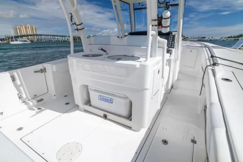 Slide: The Image of 2023 Robalo R302 Center Console boat interior with storage and seating, docked near a bridge. - 24