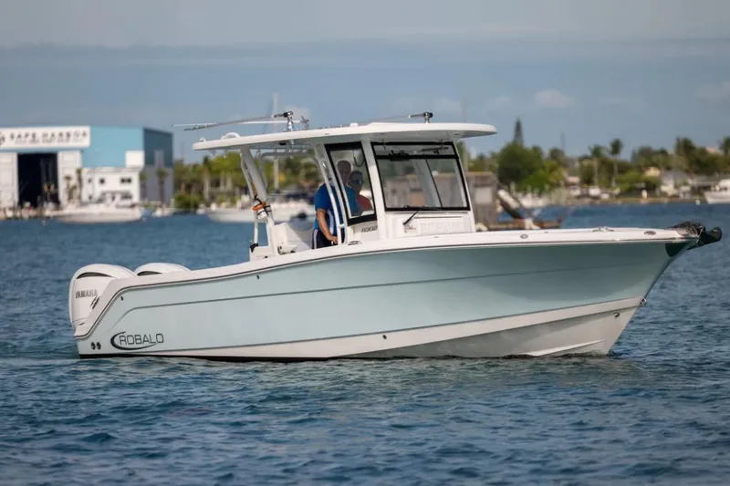 Slide: The Image of 2023 Robalo R302 Center Console boat cruising on calm waters near a marina. - 5