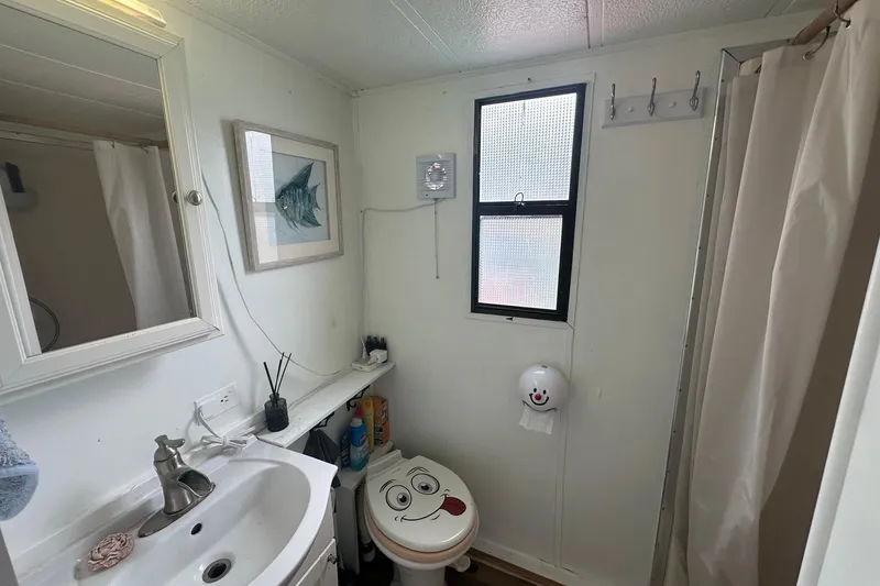 Slide: The Image of Bathroom interior of a 1996 Catamaran Cruisers 12x42, featuring a sink, toilet, and shower. - 10
