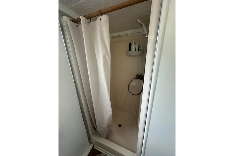 Slide: The Image of Shower area inside a 1996 Catamaran Cruisers 12x42 boat, featuring a curtain and toiletries. - 12