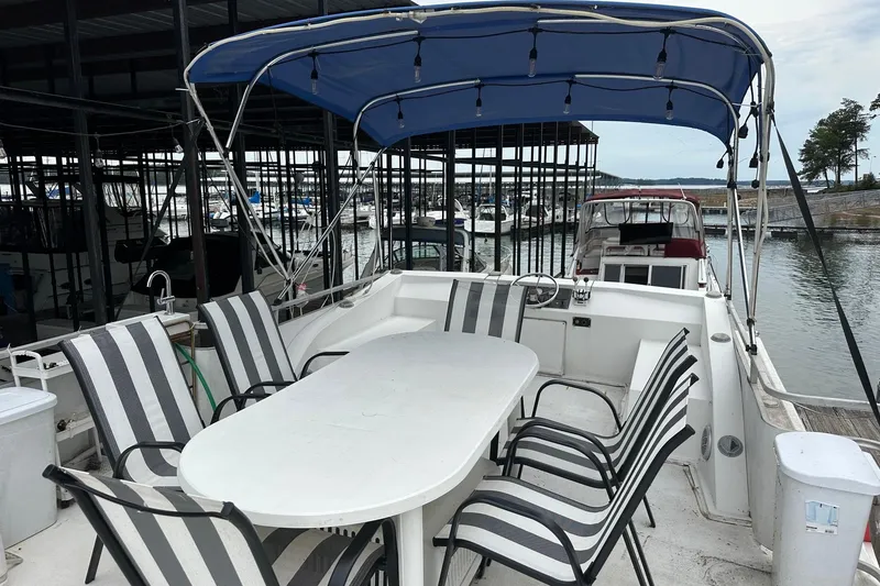 Slide: The Image of 1996 Catamaran Cruisers 12x42 with outdoor seating, docked in a marina under a blue canopy. - 14