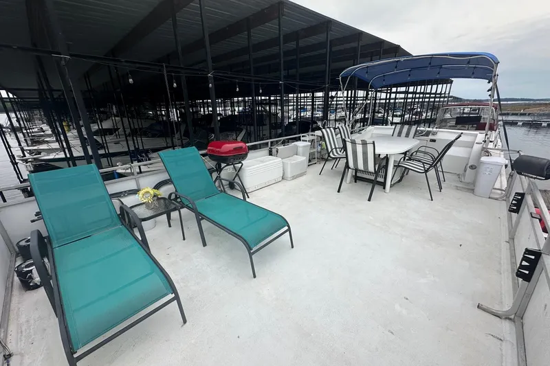 Slide: The Image of 1996 Catamaran Cruisers 12x42 houseboat with deck chairs, dining table, and grill. - 15