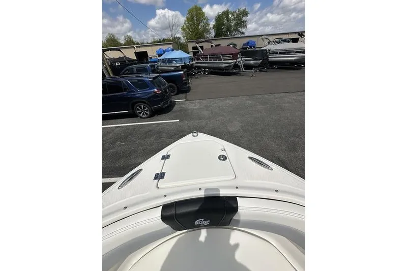 Slide: The Image of 2023 Chaparral 23 Surf boat in a parking lot with other vehicles and boats. - 13