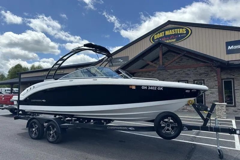 Slide: The Image of 2023 Chaparral 23 Surf boat on trailer at dealership, under a partly cloudy sky. - 2