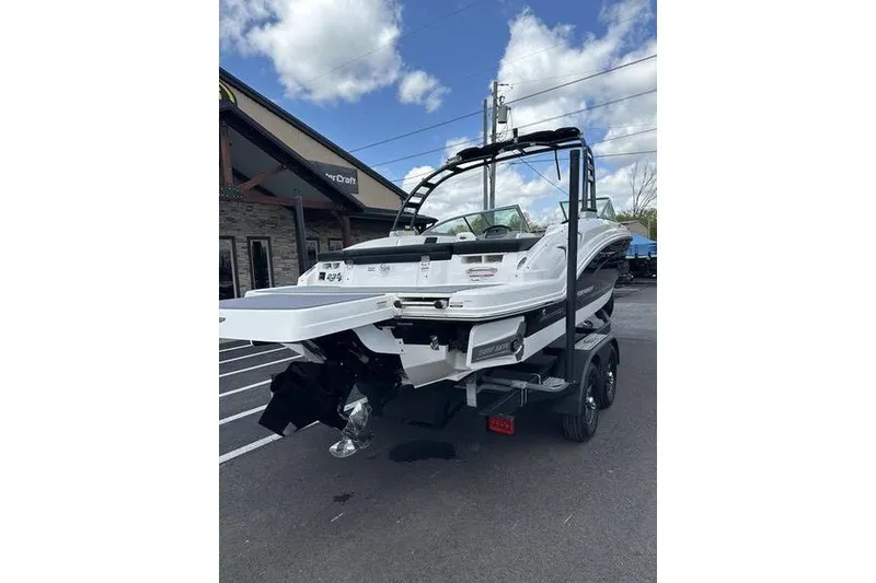 Slide: The Image of 2023 Chaparral 23 Surf boat on trailer, parked outdoors under a blue sky. - 21