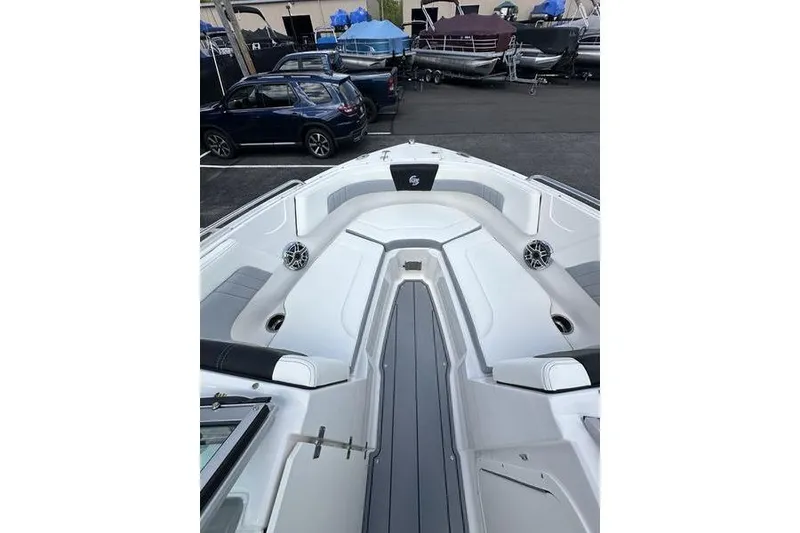 Slide: The Image of 2023 Chaparral 23 Surf boat interior with seating and speakers, parked in a marina. - 24
