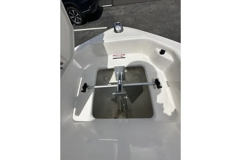Slide: The Image of 2023 Chaparral 23 Surf boat anchor compartment with metal fittings and white interior. - 26