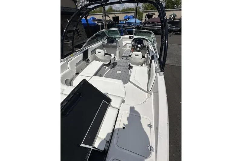 Slide: The Image of 2023 Chaparral 23 Surf boat interior with seating and steering wheel, docked outdoors. - 3