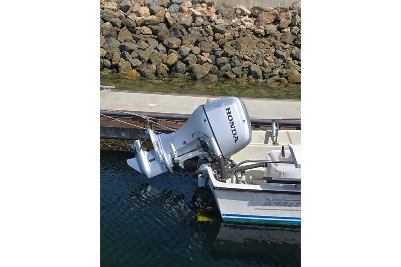 Slide: The Image of Boston Whaler 17 Montauk 1993 with Honda outboard motor docked by rocky shoreline. - 3