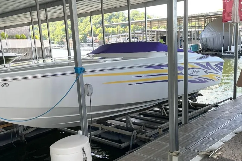 Slide: The Image of 2004 Baja 25 Outlaw speedboat with vibrant graphics docked in a marina. - 3
