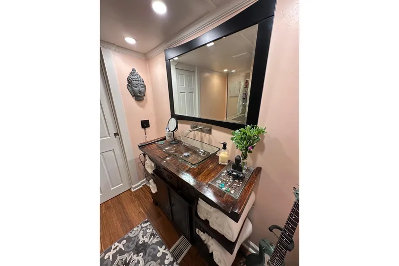 Slide: The Image of Elegant bathroom vanity with large mirror, Buddha decor, and wooden countertop in a 1993 Lazy Days 16x65. - 10