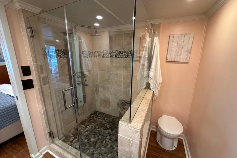 Slide: The Image of Modern bathroom with glass shower, pebble floor, and beige tiles in a 1993 Lazy Days 16x65 model. - 11
