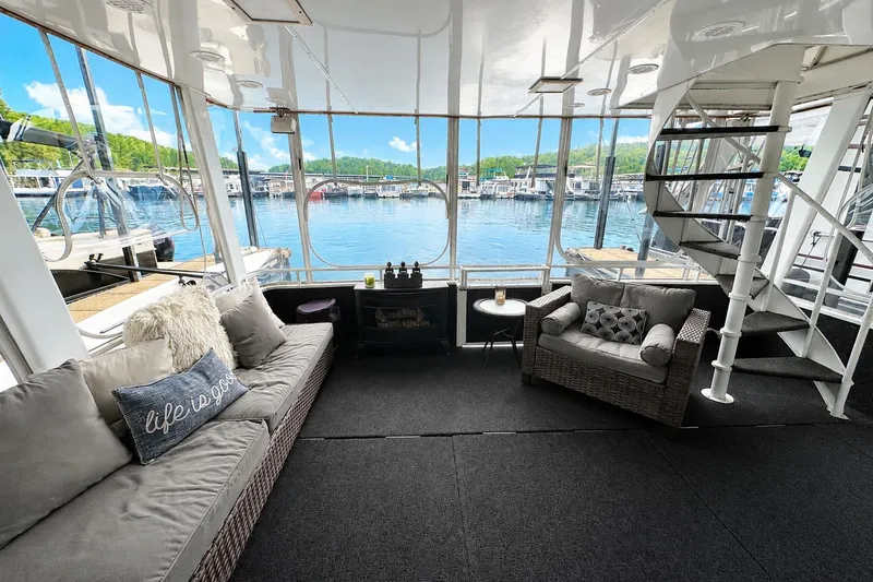 Slide: The Image of Houseboat interior with cozy seating, spiral staircase, and marina view. Lazy Days 16x65, 1993 model. - 12