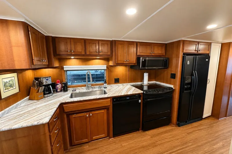Slide: The Image of 1993 Lazy Days 16x65 kitchen with wooden cabinets, marble countertops, and modern appliances. - 4