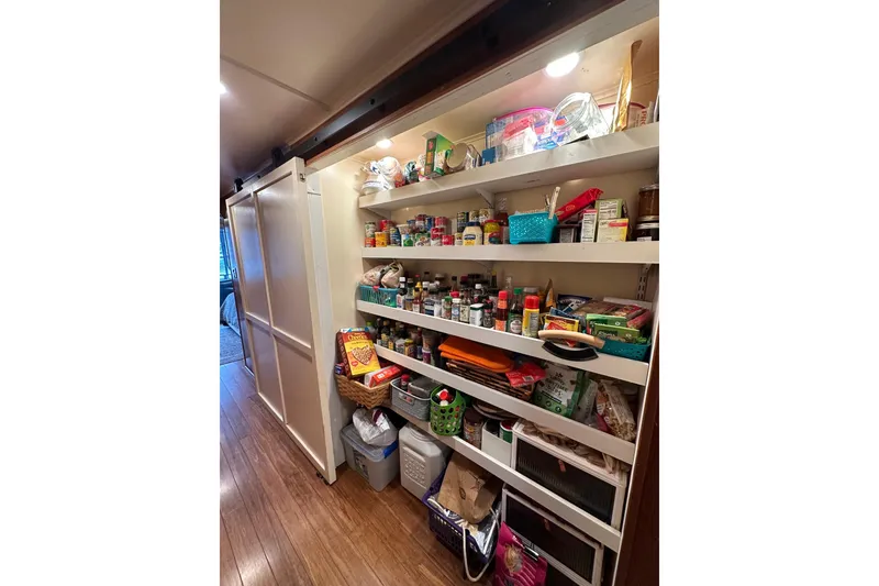 Slide: The Image of Organized pantry shelves in a 1993 Lazy Days 16x65 houseboat, stocked with various food items. - 6
