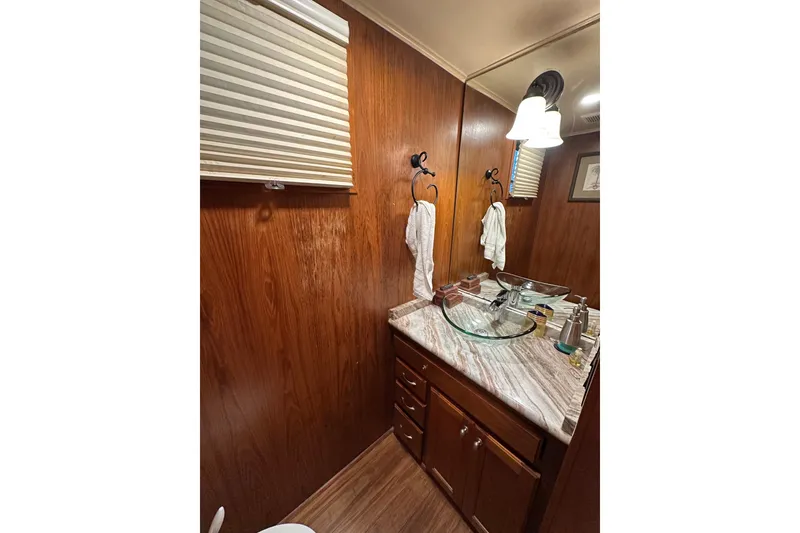 Slide: The Image of Bathroom interior of 1993 Lazy Days 16x65 houseboat with wood paneling and glass sink. - 7