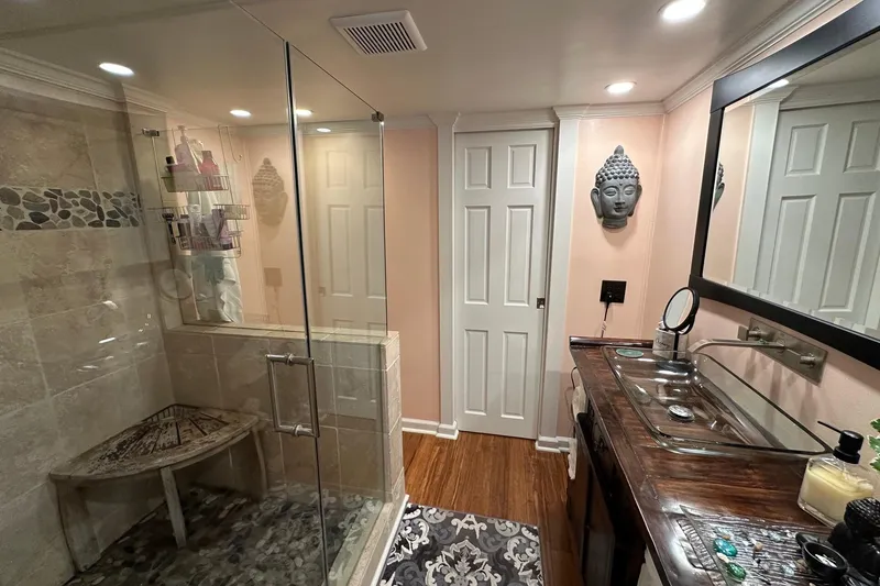 Slide: The Image of Modern bathroom with glass shower, wooden vanity, and decorative Buddha wall art in a 1993 Lazy Days model. - 9