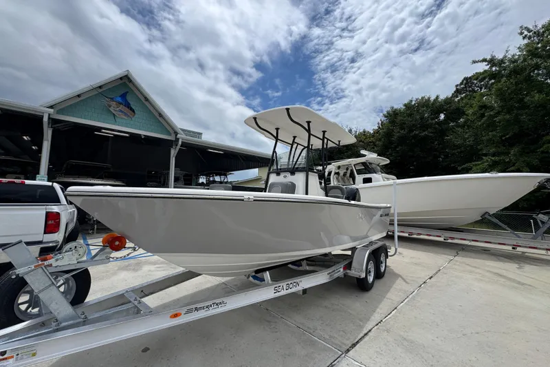 Slide: The Image of 2026 Sea Born LX21 Center Console boat on trailer, parked outside a marina. - 3