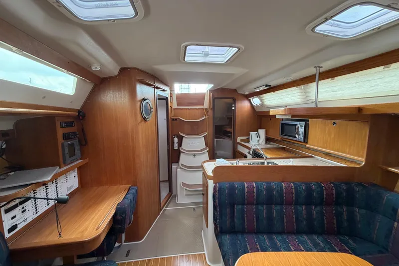 Slide: The Image of Interior of a 2001 Catalina 380 sailboat featuring a cozy dining and kitchen area. - 8