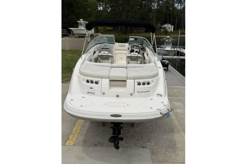 Slide: The Image of 2007 Chaparral 236 SSi boat with white seating, docked near a wooded area. - 3