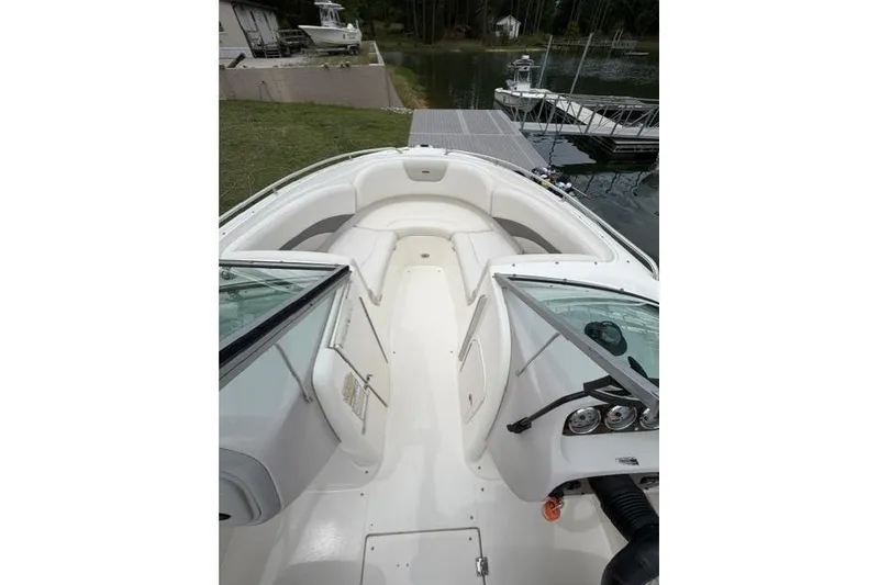 Slide: The Image of 2007 Chaparral 236 SSi boat interior with white seating and dashboard, docked by a lake. - 9