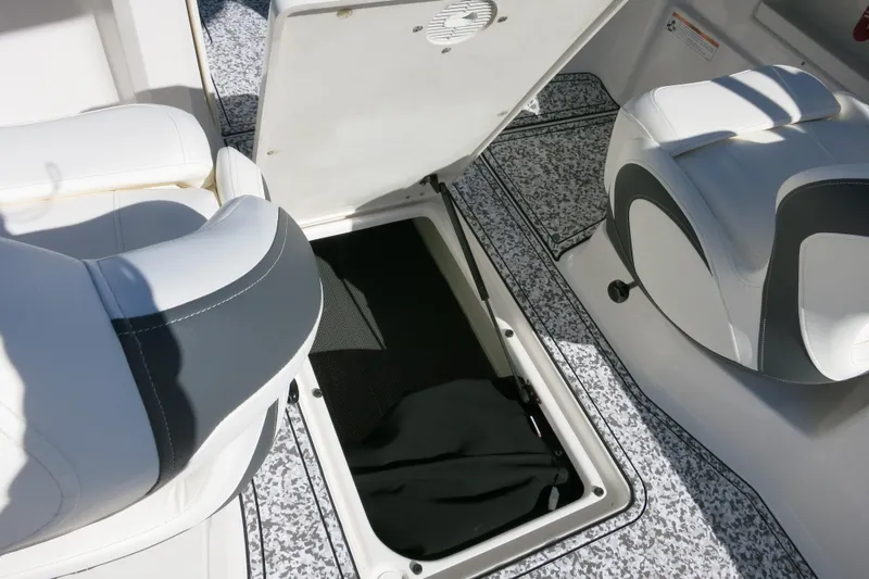 Slide: The Image of 2024 Chaparral 23 SSi OB boat interior with open storage compartment and cushioned seating. - 14