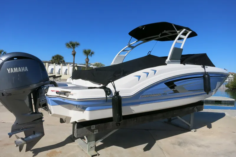 Slide: The Image of 2024 Chaparral 23 SSi OB boat with Yamaha outboard engine, docked under clear blue sky. - 2