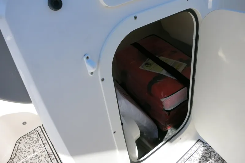 Slide: The Image of Storage compartment in 2024 Chaparral 23 SSi OB boat, featuring safety equipment. - 34