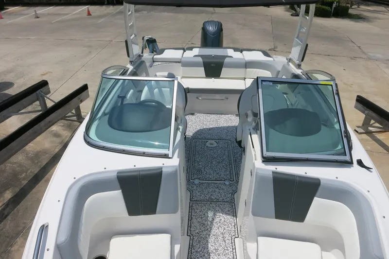 Slide: The Image of 2024 Chaparral 23 SSi OB boat interior with seating and windshield, docked outdoors. - 47
