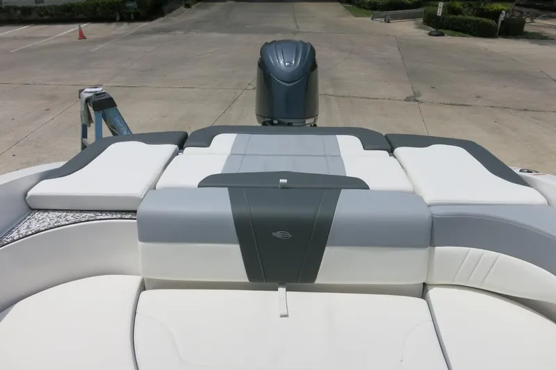 Slide: The Image of 2024 Chaparral 23 SSi OB boat with sleek seating and outboard motor in a parking area. - 54