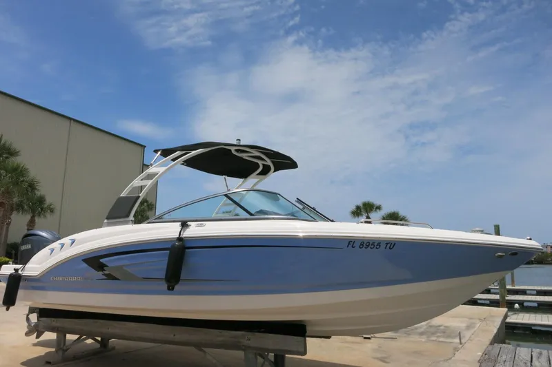Slide: The Image of 2024 Chaparral 23 SSi OB boat with sleek design, docked under a clear blue sky. - 58