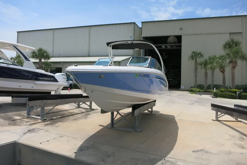 Slide: The Image of 2024 Chaparral 23 SSi OB boat displayed outdoors near a warehouse. - 60