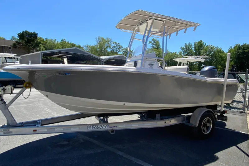 Slide: The Image of 2015 Tidewater 198 CC Adventure boat on trailer, parked outdoors under clear blue sky. - 6