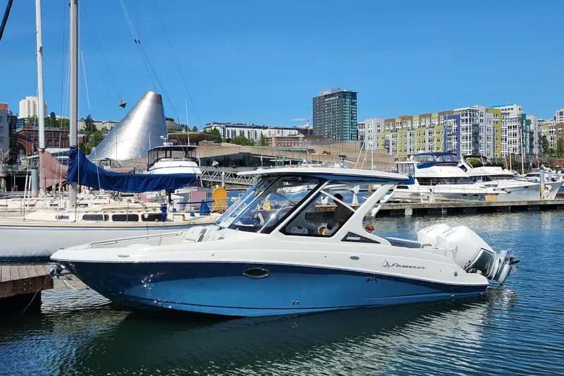 The Image of 2022 Finseeker 280 DC boat docked in a marina with cityscape background. - 0