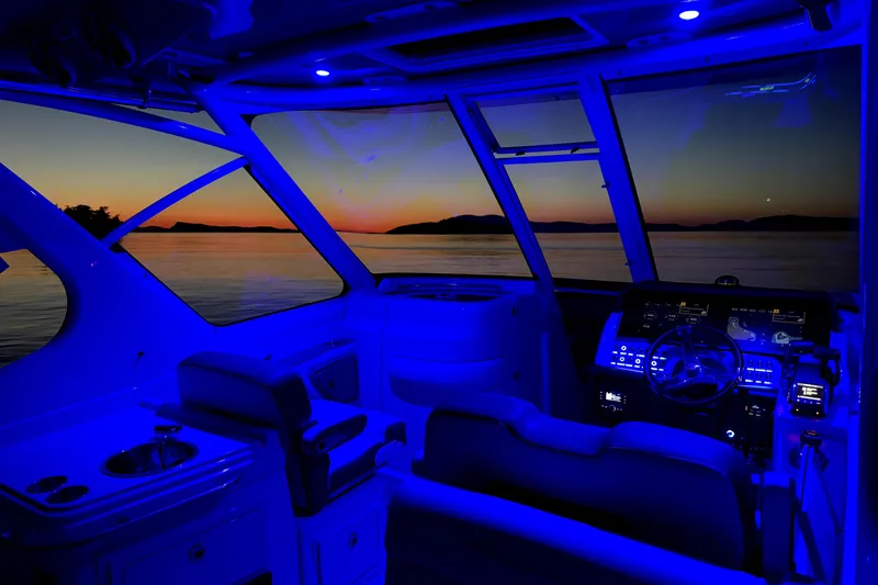 Slide: The Image of 2022 Finseeker 280 DC boat interior with blue lighting at sunset on the water. - 13