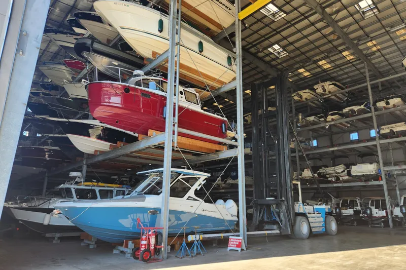 Slide: The Image of Indoor boat storage featuring a 2022 Finseeker 280 DC among stacked vessels. - 14