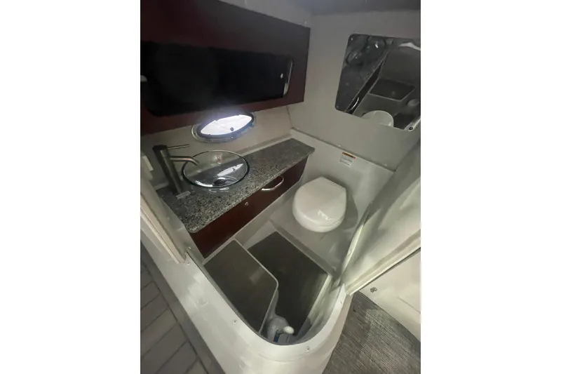 Slide: The Image of 2022 Finseeker 280 DC boat bathroom with modern sink, toilet, and porthole window. - 18